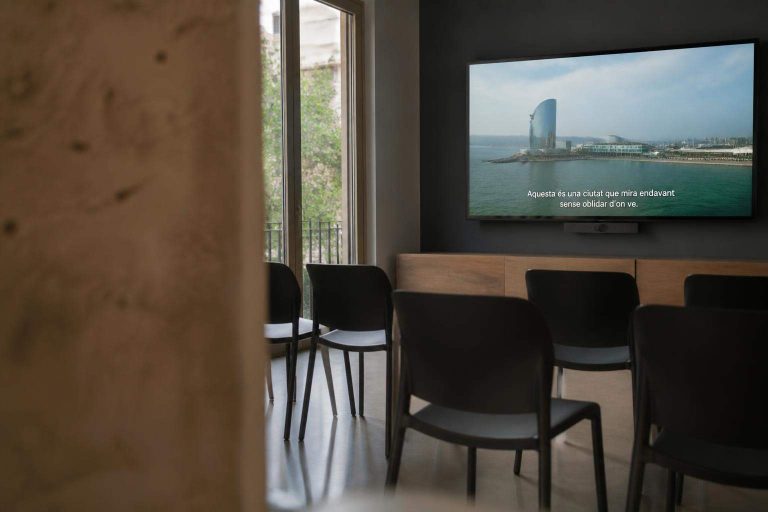Sala corporativa con un vídeo profesional en catalán proyectado en una pantalla